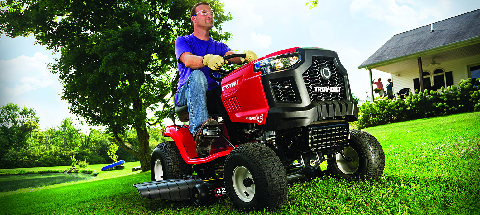 Riding mower working through a green residential yard